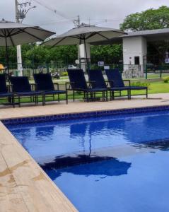 uma piscina com cadeiras azuis e guarda-sóis em Studio Garden 01 Quartos em Caruaru