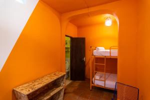 a room with an orange wall with a bunk bed at Why Not Hotel in Antigua Guatemala