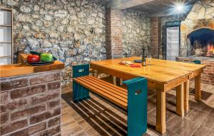 Cozy Home In Vrgorac With Outdoor Swimming Pool في Vrgorac: غرفة طعام مع طاولة خشبية وجدار حجري