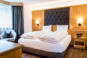 una habitación de hotel con una cama grande y una silla en Garni Hotel Mirabel en Ortisei