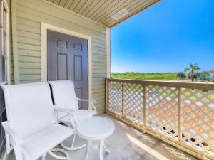 a balcony with two white chairs and a table at NEW!! 2BR 4 Beds Condo with Pool in Galveston