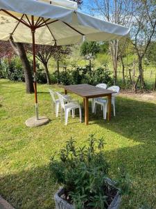 une table et des chaises en bois sous un parasol dans l'établissement Casa “ la guazzara “, à Monticiano