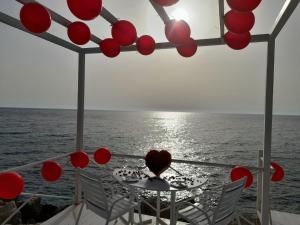 een tafel met rode ballen op de oceaan bij Four Seasons Halat in Jbeil