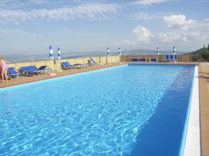 a large blue swimming pool with blue chairs and a sky at Apartment Il Casino numero 5 in Lajatico