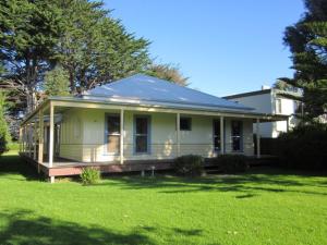 a small white house with a porch on a lawn at Timber & Tide Cottage in Cowes