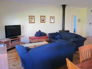 a living room with two blue chairs and a tv at Timber & Tide Cottage in Cowes