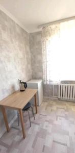 Pokój z drewnianym stołem i oknem w obiekcie Циолковского с кодовым замком w mieście Uralsk