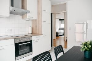 uma cozinha com armários brancos e uma mesa e cadeiras em F&E Apartment - groß, freundlich hell em Fellbach