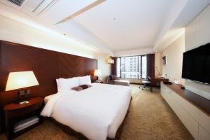 ein Hotelzimmer mit einem großen Bett und einem Fernseher in der Unterkunft Koreana Hotel in Seoul