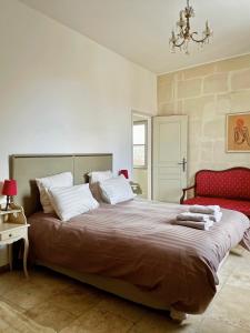 a bedroom with a large bed and a red chair at Appartement aux Arènes in Arles