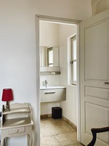 a white bathroom with a sink and a mirror at Appartement aux Arènes in Arles