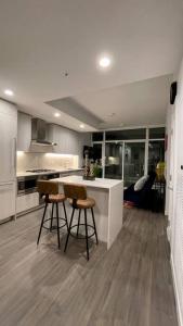 a kitchen with two bar stools and a counter at Brand New Starling Luxury Condo with Mountain Views in Burnaby