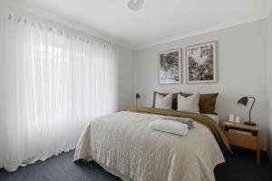 een slaapkamer met een groot bed met witte gordijnen bij 165 Back Beach Road Smiths Beach in Smiths Beach