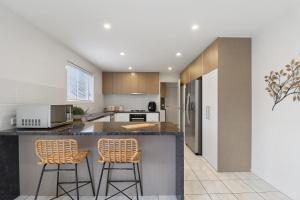 a kitchen with two bar stools at a counter at Retreat on Gairloch I Geelong River Hideaway in Geelong
