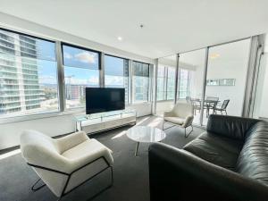 a living room with a couch and chairs and a television at Q1 709 7th floor in Gold Coast