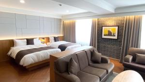 a hotel room with two beds and a couch at Commodore Hotel Gyeongju in Gyeongju