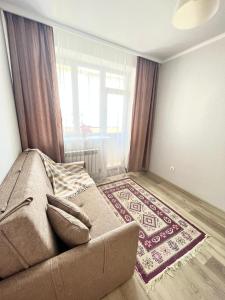 a living room with a couch in front of a window at Go to in Astana