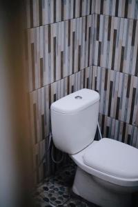 a white toilet in a bathroom with a wall at D Black Houze Banyuwangi in Banyuwangi