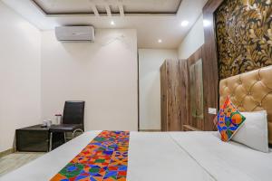 a bedroom with a bed and a chair and a desk at FabExpress Shri Ram Kashi in Prayagraj