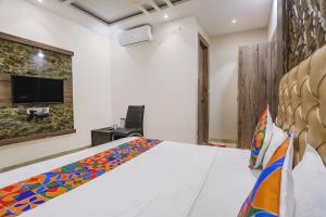 een slaapkamer met een bed en een tv aan de muur bij FabExpress Shri Ram Kashi in Prayagraj