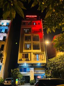 Ðoan XáにあるThanh Bình Hotelの赤い看板が立つ高層ビル
