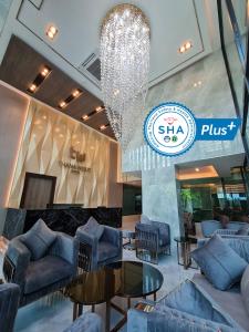 a lobby with couches and tables and a chandelier at Thana Wisut Hotel - SHA Plus in Bangkok