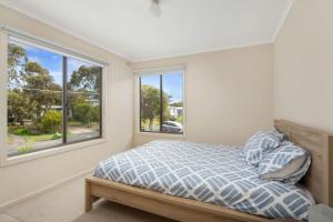 a bedroom with a bed and two windows at Seven on Ophir in Ventnor