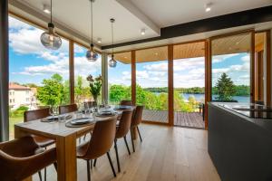 a dining room with a table and chairs and a large window at Oru Villa, LUXURY 3 BR APARTMENT, SAUNA, BEACH in Viljandi