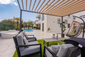 a patio with chairs and a table and a pool at Sunluxvilla ,Heated Pool, IR Sauna in Kaštela