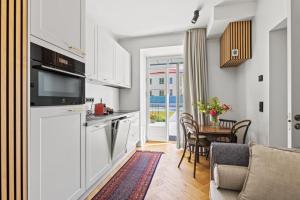 a kitchen with white cabinets and a table with a dining room at Brand New Old Town Apartment With Terrace in Haapsalu