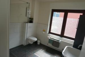 a bathroom with a toilet and a sink and a window at Ferienwohnung Familie Kirsten in Piesport +7 photos