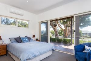 Schlafzimmer mit einem Bett und einer Glasschiebetür in der Unterkunft Red Rocks Beach Retreat Free Wifi and Foxtel in Cowes