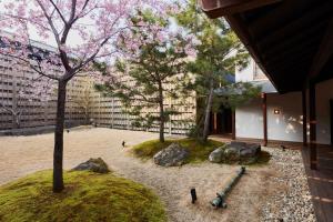 a garden with two trees and rocks in front of a building at Azumi Setoda in Onomichi