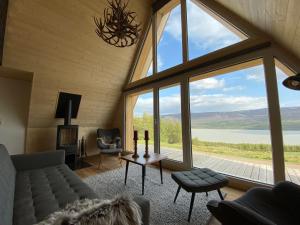 a living room with a couch and a large window at Hengifosslodge Tiny Houses in Egilsstadir
