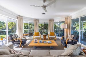a living room with a couch and chairs and windows at Celeste, 26 Bonito Street - Tranquil, Stylish & Pet friendly in Corlette