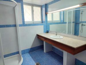 y baño de azulejos azules con lavabo y ducha. en ASTY, en Mytilini