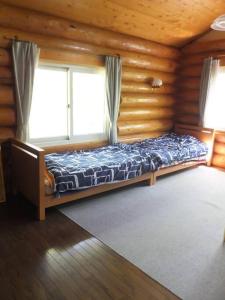 a bed in a wooden room with a window at 登別市ログハウス in Noboribetsu