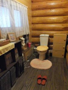 a bathroom with a toilet and a wooden wall at 登別市ログハウス in Noboribetsu