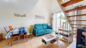 uma sala de estar com um sofá azul e uma mesa em Le Cottage des Fontenelles em Coëx