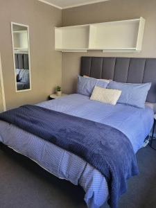 a large bed with a blue comforter in a bedroom at Even Closer to the Forest in Rotorua