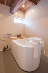 a white bath tub in a bathroom with a sink at FARMSTAY miyuki-street "Goen" in Ukiha