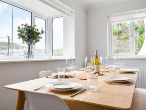a dining room with a wooden table and windows at Fairwinds in Portreath