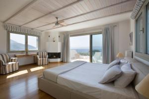 a large bedroom with a large bed and windows at Villa Elena Loutraki in Loutraki