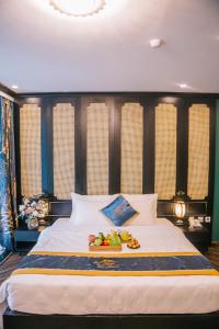 een groot bed met een dienblad met fruit erop bij Alee HaLong Hotel in Ha Long