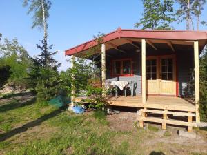 a small house with a wooden porch and a deck at Domek nad jeziorem Gowidlińskim in Podiazy