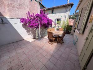 a small patio with a table and purple flowers at Maison dans les rues piétonnes du vieux Hyères in Hyères