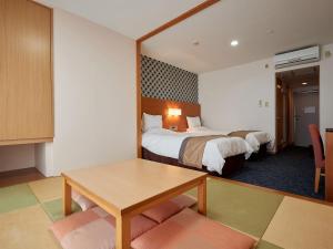 Habitación de hotel con 2 camas, mesa y espejo en Hotel Murasakimura, en Yomitan