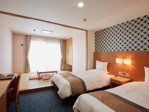 a hotel room with two beds and a window at Hotel Murasakimura in Yomitan