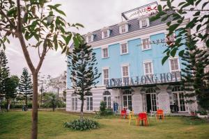een blauw en wit gebouw met kleurrijke tafels en stoelen bij Alee HaLong Hotel in Ha Long