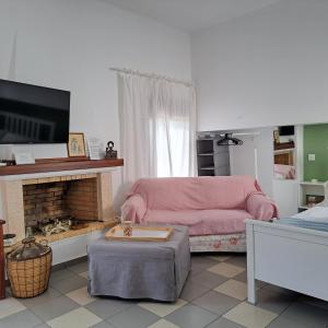 sala de estar con sofá rosa y chimenea en BaSiLiKoS, en Perdika